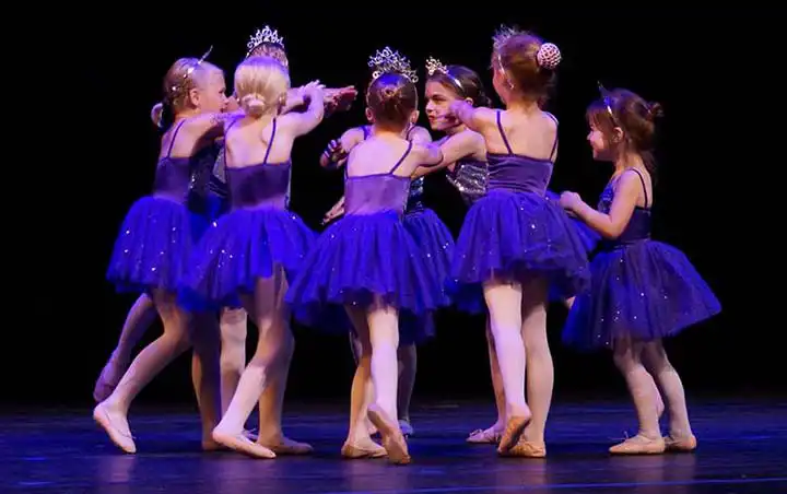 A circle of ballet dancers in bright blue tutus